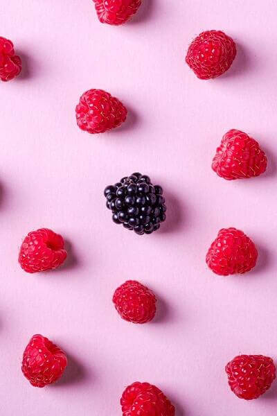raspberries and blackberry on pink background